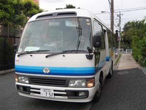 白い車体に3色の青いラインが入った社員の通勤用マイクロバスの写真バス