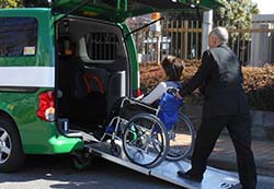 車椅子利用のお客様をドライバーが介助してユニバーサルデザインタクシーにスロープから乗車されている写真